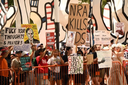 people hold signs saying ‘nra kills kids’ and ‘Guns over people’ with the letters G. O. P. highlighted