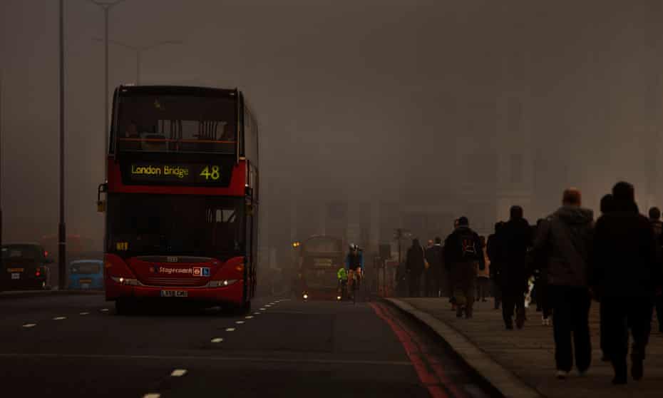Pedestrians and traffic in smog on London Bridge.