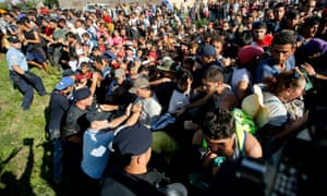 Migrants push policemen during a stampede to board buses in Tovarnik, Croatia
