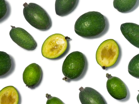Whole and halved feijoas on a white background.
