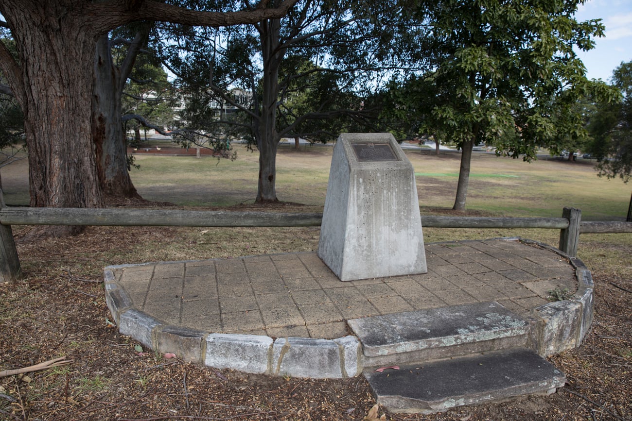 A plaque on a concrete plinth beside a park