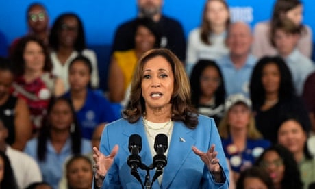 a woman in a blue suit speaks to a crowd of people