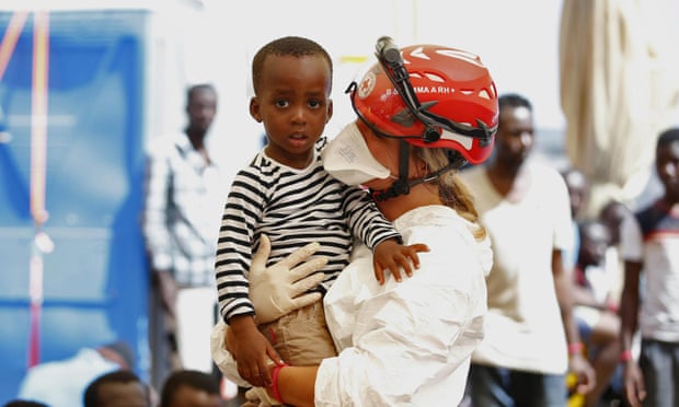 Italian Red Cross crew member helps a migrant child