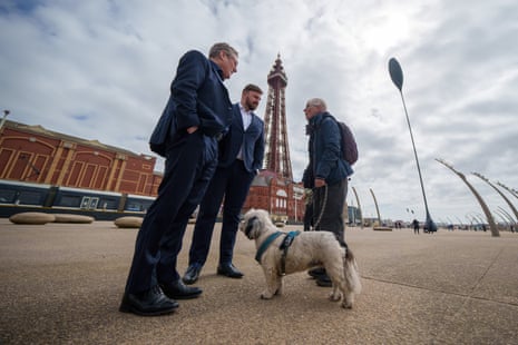 Labour party leader Keir Starmer and the party's candidate for Blackpool South Chris Webb talk to a member of the public and their dog on the promenade in Blackpool.