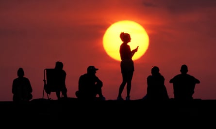 People turn out to watch the sunrise at Cullercoats Bay, North Tyneside, on a 40C day in the UK