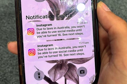 A teenager holds a mobile phone displaying a message from a social media platform