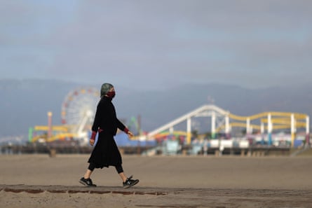 A woman walks the beach in Santa Monica. Southern California is seeing a particularly troubling rise in cases.