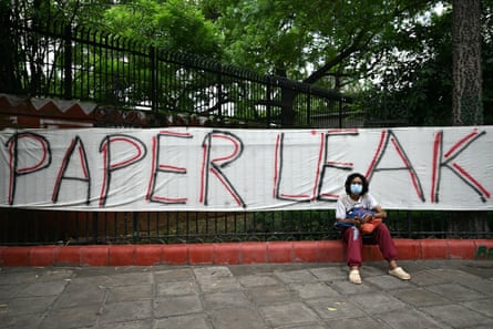 A person sits in front of a banner with the words ‘Paper Leak’