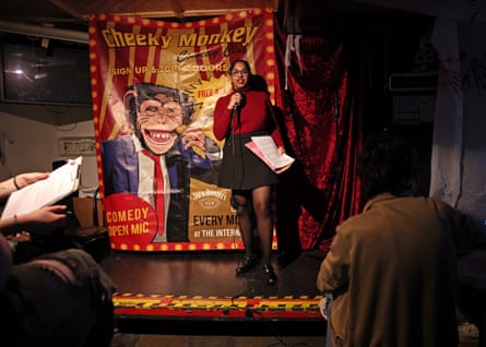 Jaishree Malik holds a microphone and her deportation papers during a comedy performance