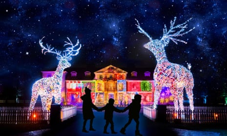 Christmas illuminations at Dunham Massey, showing three silhouetted figures holding hands between two large lit-up reindeer and the lit-up building behind