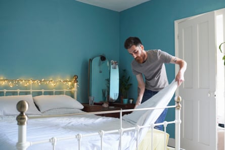A young man making a bed