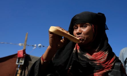 A displaced Yemeni woman eats a loaf of bread
