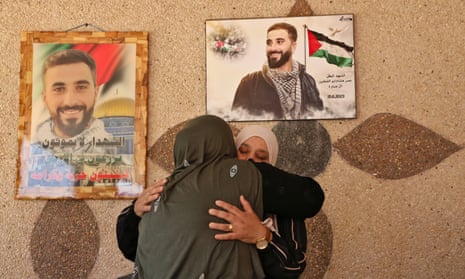 A woman comforts Hanan Qattin in her home against pictures of her son Omar, killed by gunfire during an attack by Israeli settlers in the West Bank village of Turmus Ayya
