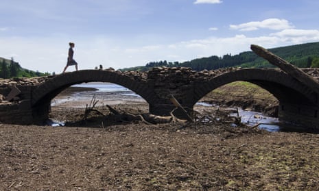 A woman crosses a bridge at the Llwyn-on reservoir, near Merthyr Tydfil, Wales, which has vastly reduced water levels as a result of the heatwave