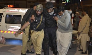 Rescuers help an injured person to a hospital in Quetta, Pakistan, after a hostel for police cadets was attacked by militants.