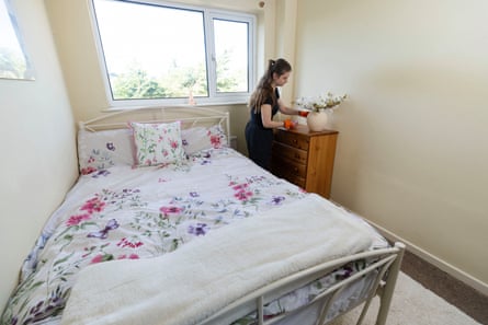 A woman wearing cleaning gloves putting the finishing touches on a clean bedroom