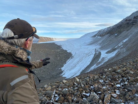 Andy Hodson, Andy Hodson, in a cap and winter coat, gestures toward a snow-streaked mountain valley