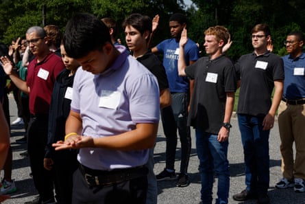 young men wearing name tags raise right hands. one man in foreground clasps hands together