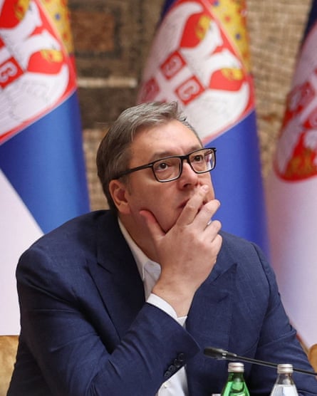 Vučić with hand on chin and flags behind