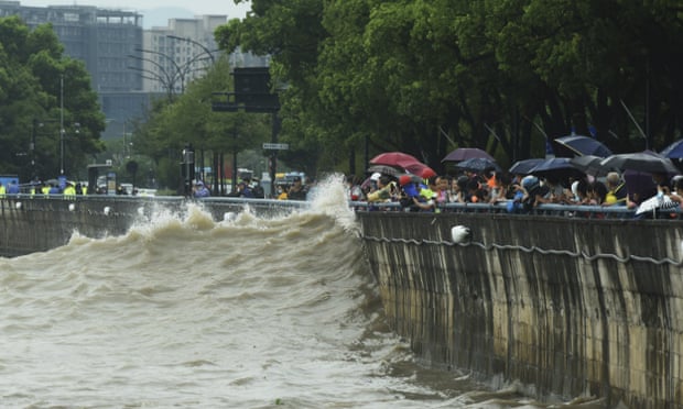 People watch the high tide along the bank of Qiantang River in Hangzhou, China, ahead of the arrival of the Typhoon Muifa.