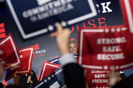 Kevin McCarthy can be seen through the arms of a crowd of people waving signs at an election watch party.