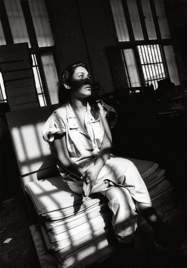 Black and white photograph of a woman sat on a prison bed staring into the distance