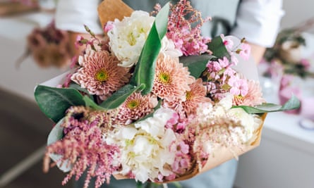 An employee of a flower boutique holds a freshly picked bouquet.