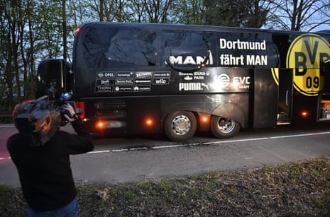 A cameraman films the Dortmund bus after it was damaged by explosions.