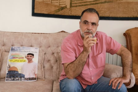 Man sitting on settee with picture of. dead son.