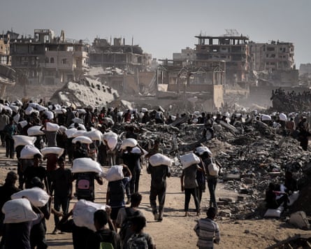 Palestinians carry sacks of food supplies near a border crossing on the Gaza Strip