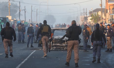 South African police near burnt-out vehicle