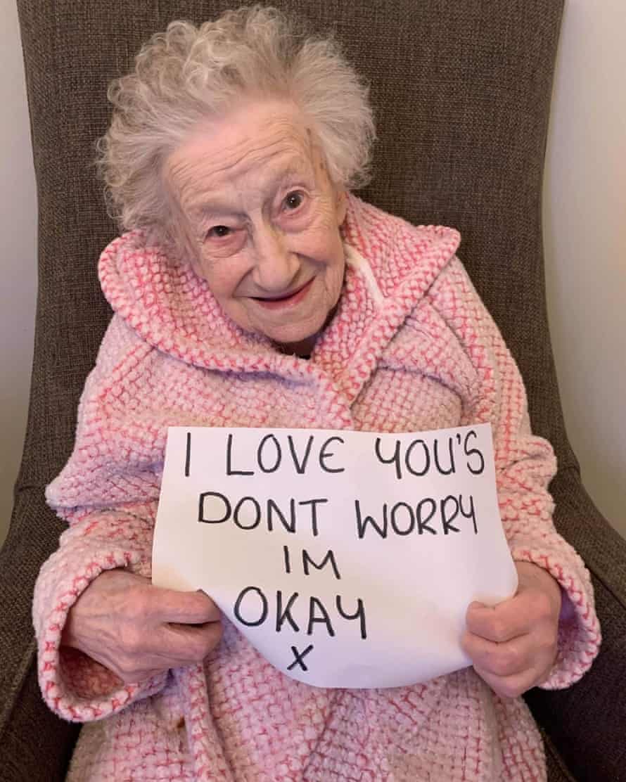 A resident at West Farm Care House Care Centre in Newcastle holds up a message reading “I love you’s don’t worry, I’m okay x”.