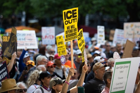 A crowd of protesters hold ‘ICE OUT!’ signs.