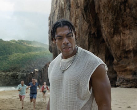A man standing on a beach near a large cliff