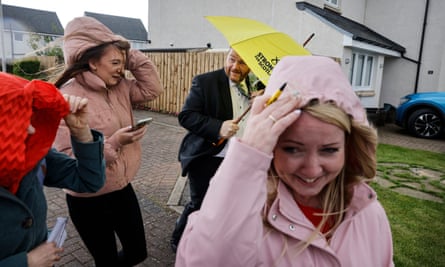 Owen Thompson holds a yellow umbrella as supporters shelter from the rain