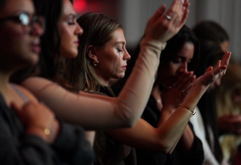 Women cry as they pray and raise their hands to the sky