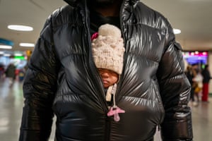 A passenger holds a child under their coat at Penn station in New York