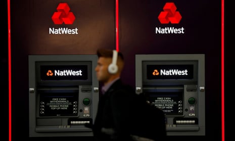 Man walks past two NatWest ATMs
