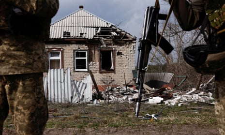 Ukrainian servicemen stand outside a destroyed building
