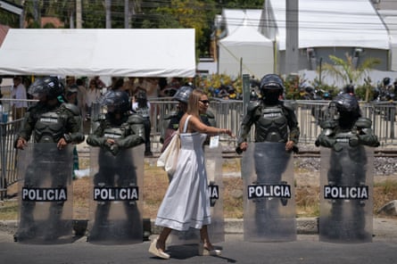 A woman walks past a row of police officers dressed in riot gear outside the summit.