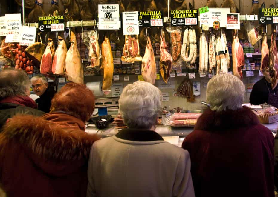 Customers wait at the counter of a ham store in Madrid.