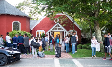 People with suitcases in front of a red church