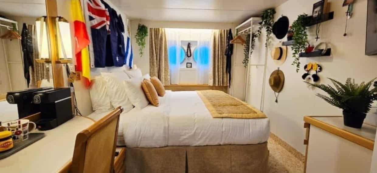 A cruise ship cabin, decorated with hats, flags and plants