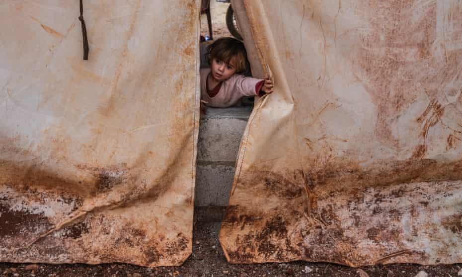 A displaced Syrian girl looks out from her tent at Abu Makki camp, outside Idlib. UK aid funding for Syria was cut by 69%.