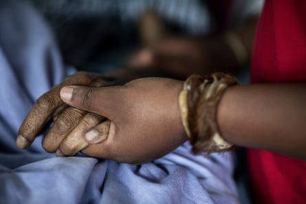 A nurse holding a patient’s hand.