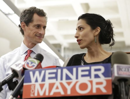 Anthony Weiner, with wife Huma Abedin, stand behind a podium with numerous microphones and a ‘Weiner for mayor’ slogan