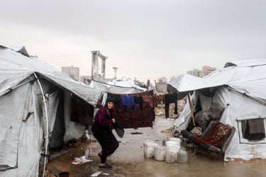 A woman gathers her belongings at a makeshift camp sheltering displaced Palestinians after heavy rains in Gaza City