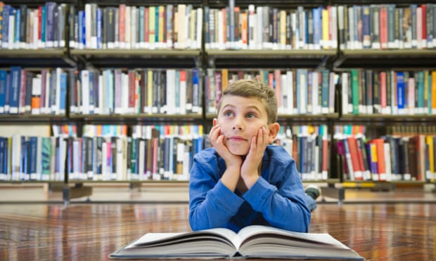 Boy with book on library floor
