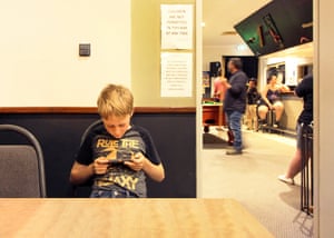 A young boy occupies himself at a venue while adults hang out in the other room.