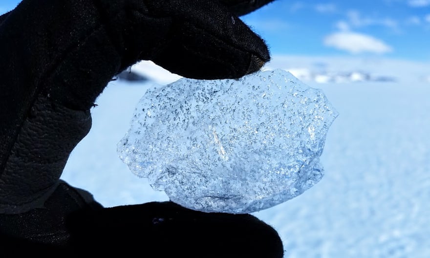 a gloved hand holding a ball of ice